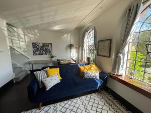 a blue couch in a living room with windows at The Old Foundry Wallingford Apartment & Parking in Wallingford