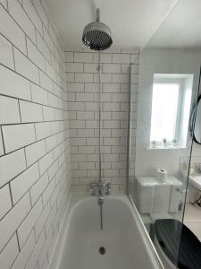 a white bathroom with a tub and a sink at The Old Foundry Wallingford Apartment & Parking in Wallingford