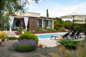 a house with a pool and chairs and an umbrella at Blumarine in Brzac