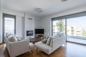 a living room with two white chairs and a table at Light in Athens
