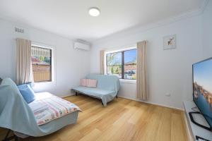 Habitación con cama, sofá y ventana en Belmore Affordable 2 Br Granny Flat, en Sídney