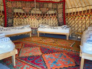 Bokonbayevo的住宿－Yurt camp Sonun，圆顶帐篷内带三张床和地毯的房间