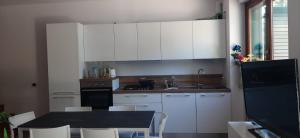 Casa Mia Sirolo في سيرولو: مطبخ مع دواليب بيضاء وطاولة وكراسي