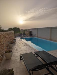 a swimming pool with tables and chairs on a building at Sea Holly Gozo in Nadur