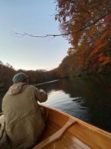 a man is sitting in a boat on the water at Urabandai Cranes in Kitashiobara