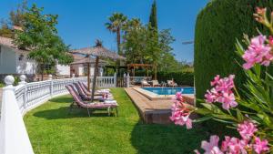 un patio trasero con piscina, sillas y flores en Casa Rural Marquez Ronda by Ruralidays, en Ronda