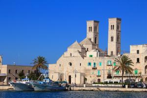 a building with two towers and a boat in the water at Sea Riad in Molfetta