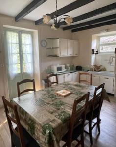 een keuken met een tafel en stoelen en een keuken met een tafel bij Maison de location saisonnière en Périgord Vert in Saint-Front-la-Rivière