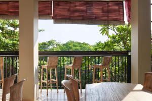 a porch with chairs and a table and a balcony at Gelatik Bed And Breakfast in Seminyak
