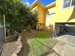 a yellow house with a fence and a yard at 2 Bedroom Apartment near Graftons Waterfront in Grafton