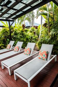 3 bancs blancs assis sur une terrasse avec des oreillers dans l'établissement Chez Brolga, à Port Douglas