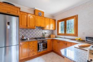 a kitchen with wooden cabinets and a stainless steel refrigerator at Villa Rafael in Cumbre del Sol