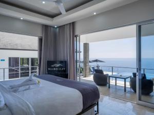a bedroom with a bed and a view of the ocean at Suluban Cliff Bali Villa in Uluwatu