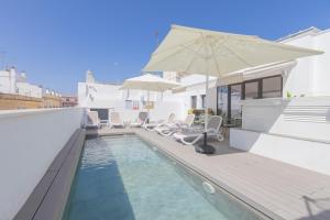einen Pool mit Stühlen und einem Sonnenschirm in der Unterkunft Soho Boutique Columela in Cádiz