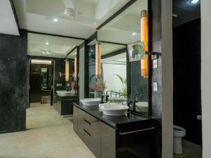 a bathroom with two sinks and two mirrors at Suluban Cliff Bali Villa in Uluwatu