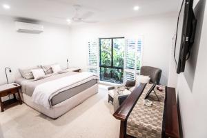 Habitación blanca con cama y ventana en Chez Brolga, en Port Douglas