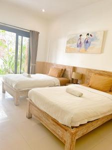 a bedroom with two beds and a painting on the wall at Lemon Guest House in Canggu