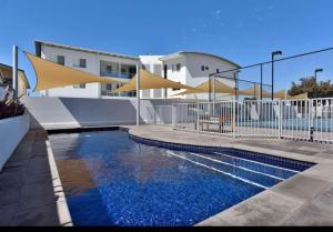 a swimming pool in front of a building at Gallery 10 with views, pool and tennis court in Victor Harbor