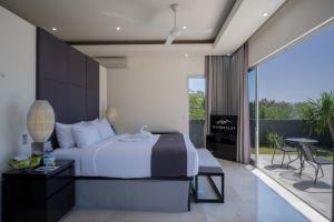 um quarto com uma cama grande e uma varanda em Suluban Cliff Bali Villa em Uluwatu