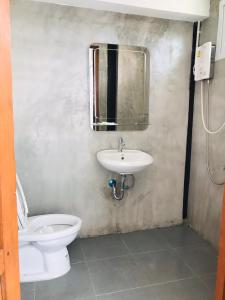 uma casa de banho com um WC, um lavatório e um espelho. em SolarCell Private Homestay - โซล่าเซลล์ไพรเวทโฮมสเตย์ em Uthai Thani