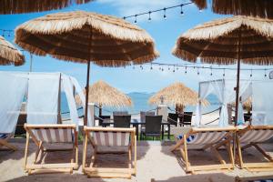 a group of chairs and umbrellas on a beach at Golden Tulip Pattaya Beachfront Resort in Pattaya North
