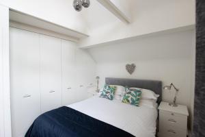 a white bedroom with a bed and white cabinets at The Penthouse Canterbury - Cathedral View in Canterbury +4 photos