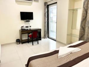 um quarto com uma cama, uma secretária e uma televisão em The Grand Suite-70 em Noida