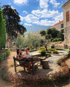 Dos mujeres sentadas en un banco en un jardín en Stone Cellars en Douma