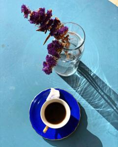 Dūmā的住宿－Stone Cellars，一块蓝色的盘子,上面有一杯咖啡和花瓶