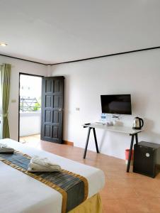 a room with two beds and a desk and a television at Blue Carina Hotel - SHA Plus in Phuket Town