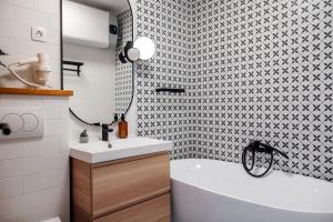 ein Badezimmer mit einer weißen Badewanne und einem Waschbecken in der Unterkunft Belváros Apartman in Veszprém