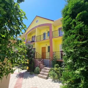 a yellow house with stairs in front of it at Guest House Moryachka in Bosteri