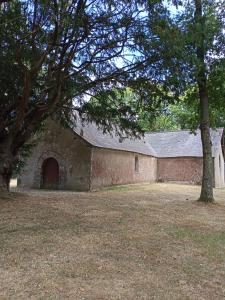 an old brick building with a door and a tree at chez christine in Sainte-Marie