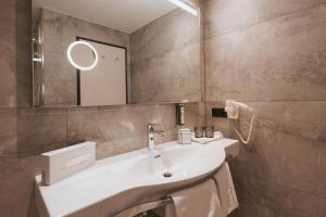 a bathroom with a white sink and a mirror at MANNI das Hotel in Mayrhofen