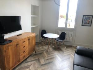 a living room with a tv and a table and chairs at Superbe appartement indépendant en centre ville in Vichy