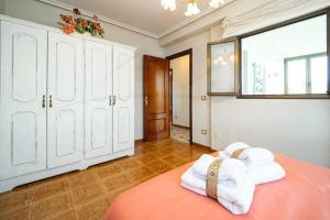 a bedroom with white cabinets and towels on a bed at La Huertina De Granda in Candanal