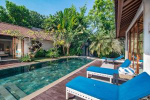 a swimming pool with blue chairs next to a house at The Akasha Luxury Villas in Seminyak