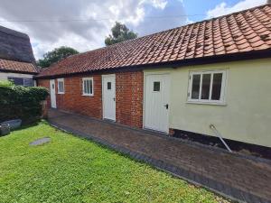 a brick house with white doors and a grass yard at Kings Head in North Lopham