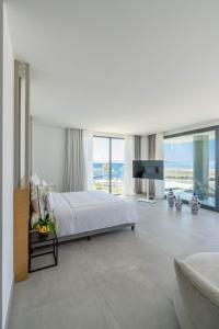 a white bedroom with a large bed and a tv at Akana Loft in Bodrum City