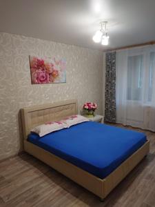 um quarto com uma cama azul e flores na parede em Квартира у метро Спортивная em Kharkov