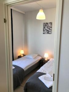 2 Betten in einem kleinen Zimmer mit 2 Lampen in der Unterkunft Kotimaailma - Kaksio saunalla Herttoniemessä in Helsinki