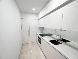 uma cozinha branca com armários brancos e um lavatório em KLCC Skysuites with Private Balcony and Terrace em Kuala Lumpur