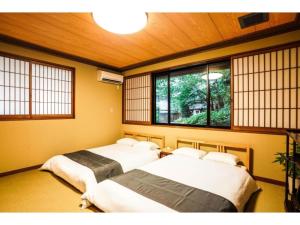 Shirakabanoyado Izumi - Vacation STAY 95387v في إيزوميسانو: سريرين في غرفة مع نوافذ في غرفة
