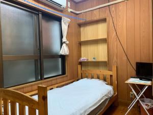 een kleine kamer met een bed en een raam bij 民宿ちねん in Uruma