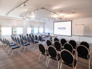 une chambre avec des chaises et un écran de projection dans l'établissement Novotel Nantes Centre Gare, à Nantes