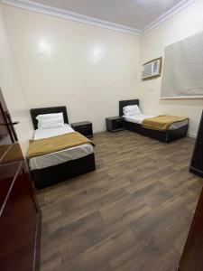 two beds in a room with wooden floors at شقق بن طالب in Khamis Mushayt
