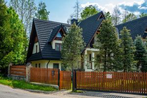 ein Haus mit einem schwarzen Dach und einem Holzzaun in der Unterkunft Poza Szlakiem in Zakopane