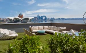 a balcony with a couch and chairs and a view of the city at Sheraton Baku Intourist in Baku