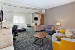a hotel room with a bed and a couch at Courtyard by Marriott Auburn in Auburn