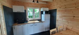 a kitchen with white cabinets and a window in a log cabin at Na Spokojnej Rodzinne Wakacje in Pogorzelica